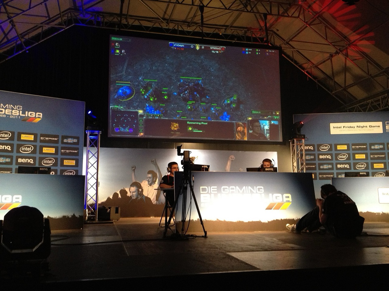 StarCraft II match displayed above player booths on an esports stage in Munich